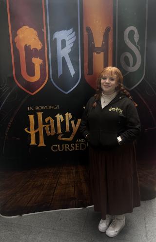 Casey Ingraham poses in front of a display for Harry Potter and the Cursed Child