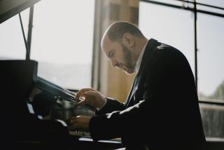 a man playing a piano in front of a sunny window