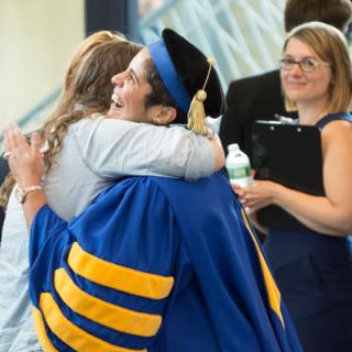 A woman in academic cap and a female student hug. 
