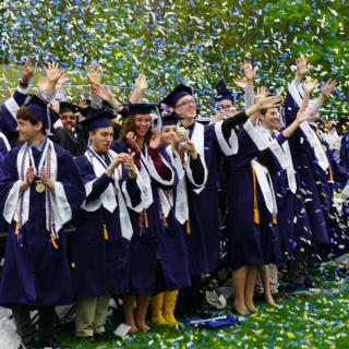 Graduates celebrate at confetti rains down.