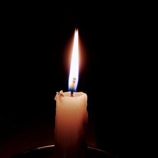 A single lit candle against a dark backdrop.