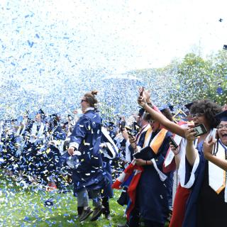 Confetti flutters over college graduates.