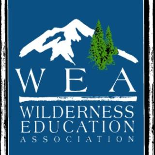 This is a logo with the picture of a mountain and some trees with the name of the organization, W, E, A or Wilderness Education Association underneath.