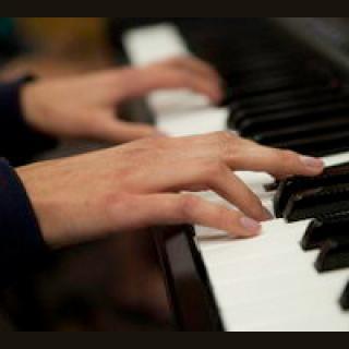 hands playing a piano keyboard