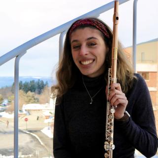 Person smiling while holding flute in hand