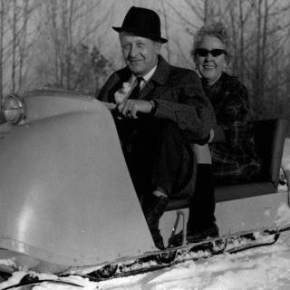 Man and woman on an old-fashioned snow mobile.