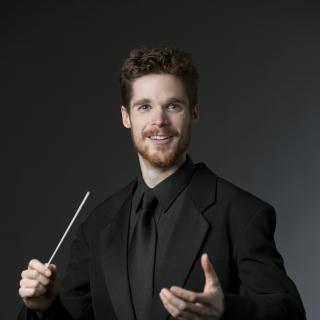 Man in a black suit holding a baton