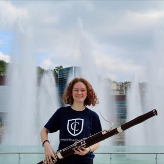 Woman holding a bassoon in front of fountains