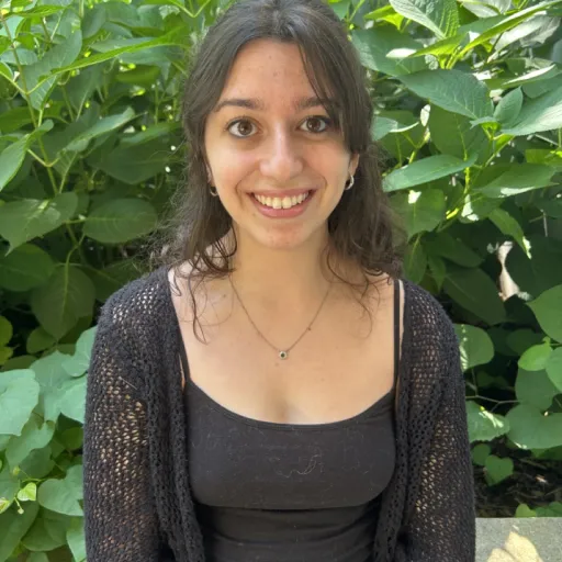 person sitting in front of bush smiling