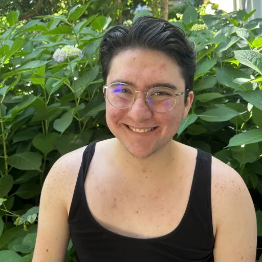 person sitting in front of bush smiling