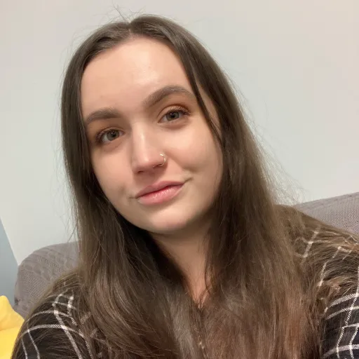 female with brown hair and plaid shirt with a soft smile 