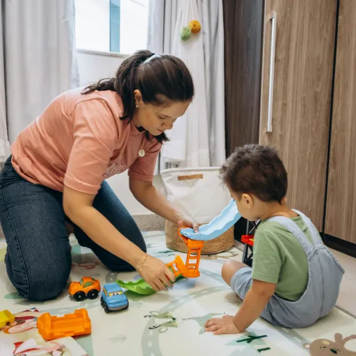 A parent and child are playing with toys on the floor