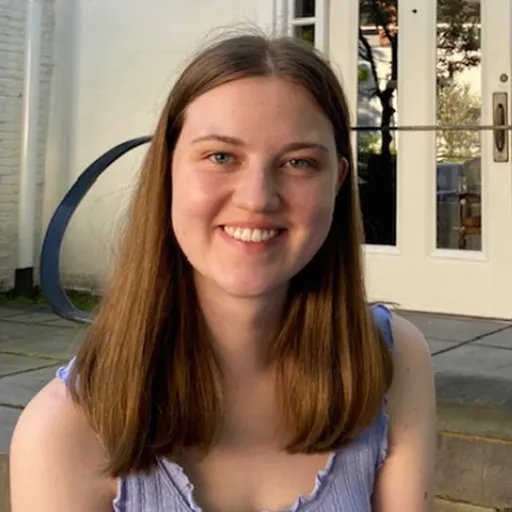 Photo of a woman's face with long hair standing in front of a building