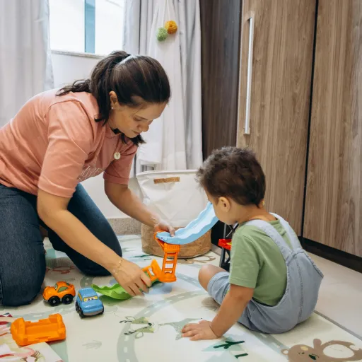 A parent and child are playing with toys on the floor